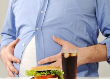 Fat belly behind burger and soda
