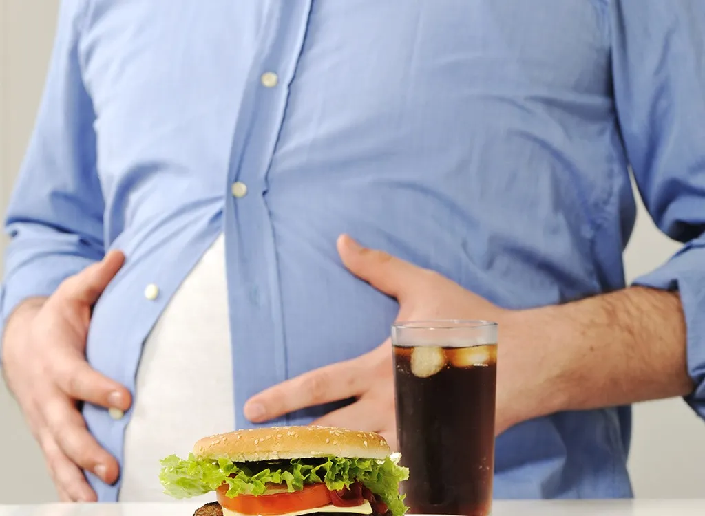 Fat belly behind burger and soda