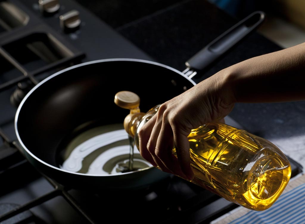 Pouring vegetable oil into skillet on stove