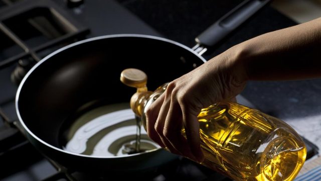 Pouring vegetable oil into skillet on stove