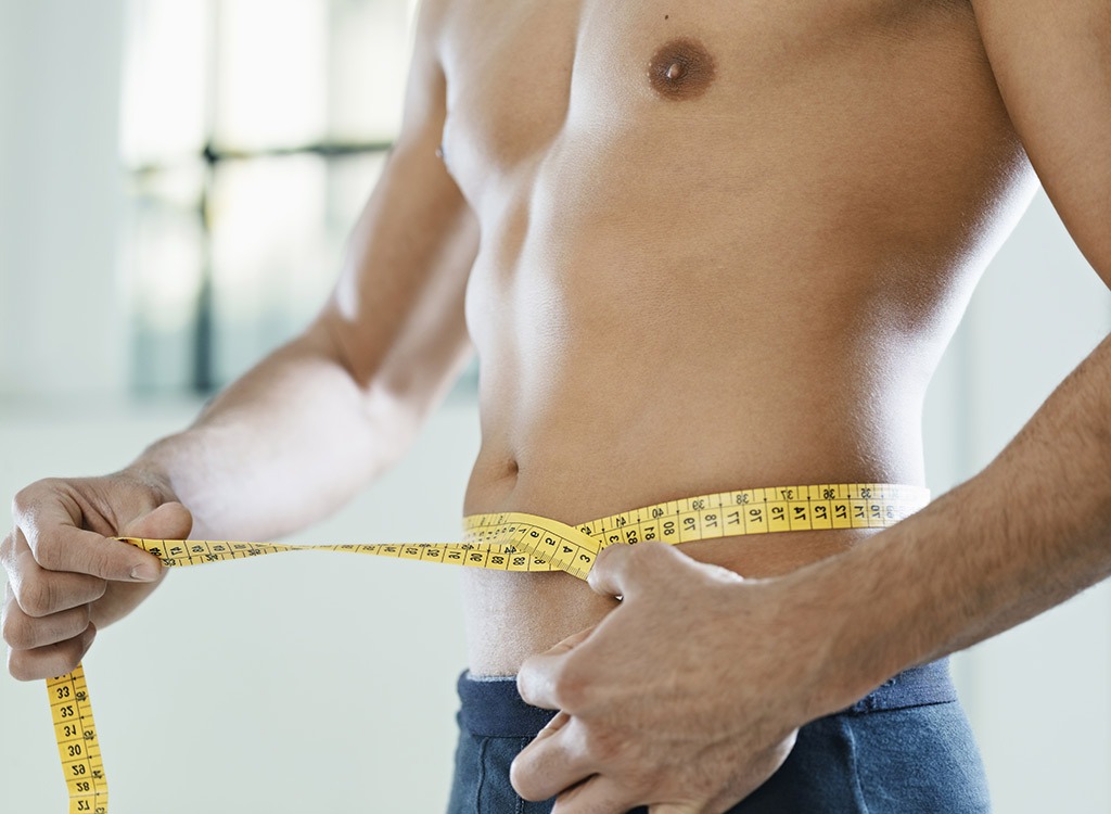 fit man measuring waist size with measuring tape