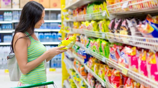 Woman shopping in supermarket snack aisle