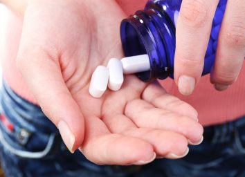 woman pouring pills into hand