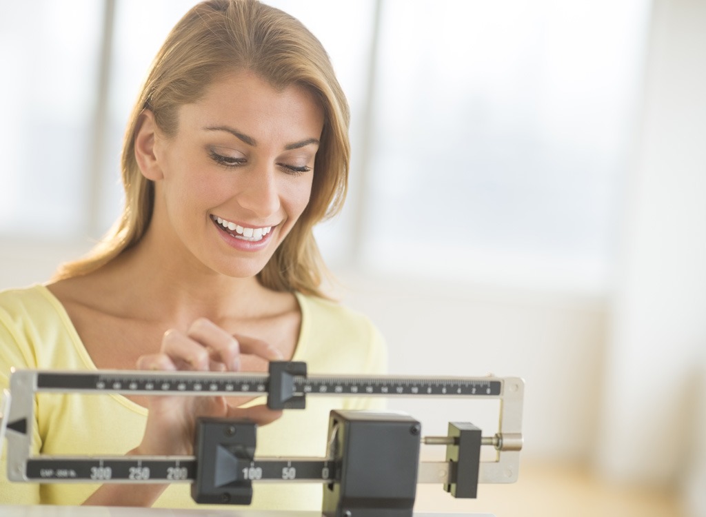 Woman Weight Loss. Smiling Woman Standing On Scale. Woman Measuring Body  Weight On Weighing Scale. Weight Loss, Diet And Dieting, Healthy Lifestyle  Concept Photos