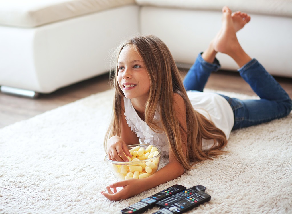 Family Sitting On Sofa In Open Plan Lounge Watching Television