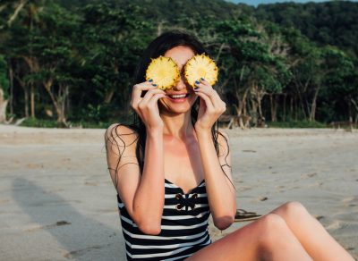 Woman on beach holding pineapple
