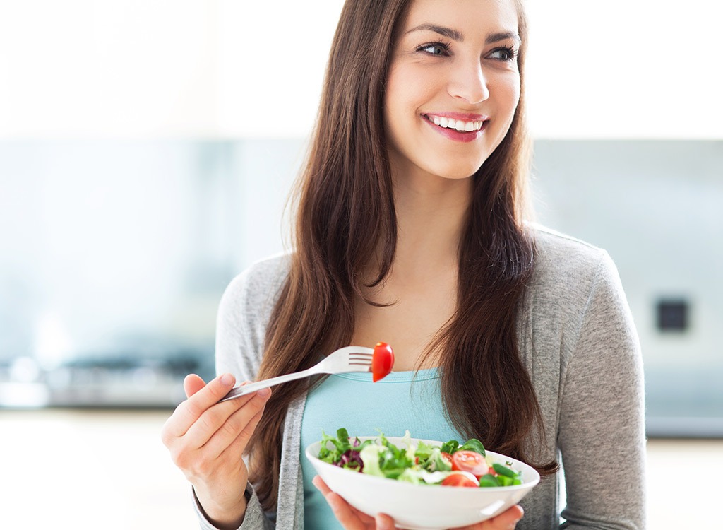 Smiling woman eating salad