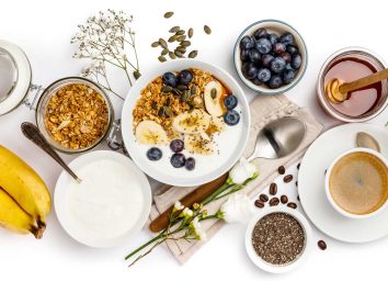 Healthy breakfast foods blueberries bananas bowl of yogurt oatmeal and coffee