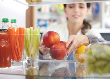 Woman reorganizing her fridge to put fresh fruits vegetables healthy snacks in front