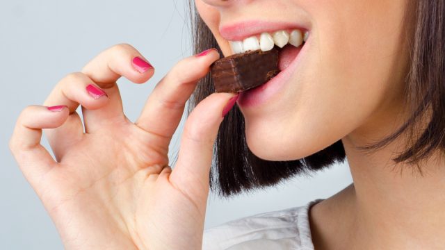 woman taking a bite of chocolate and enjoying her dessert