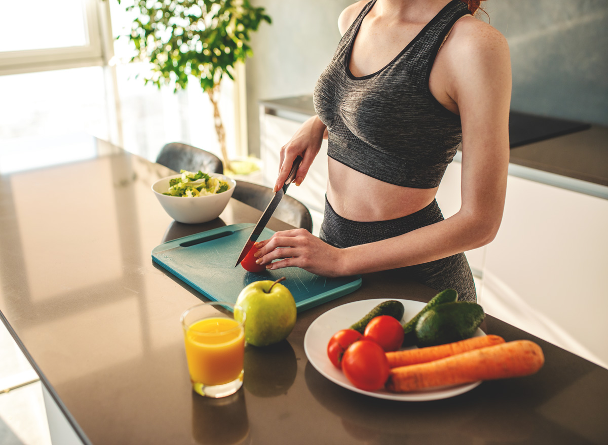 Woman wearing workout clothes at home cooking and eating after exercising