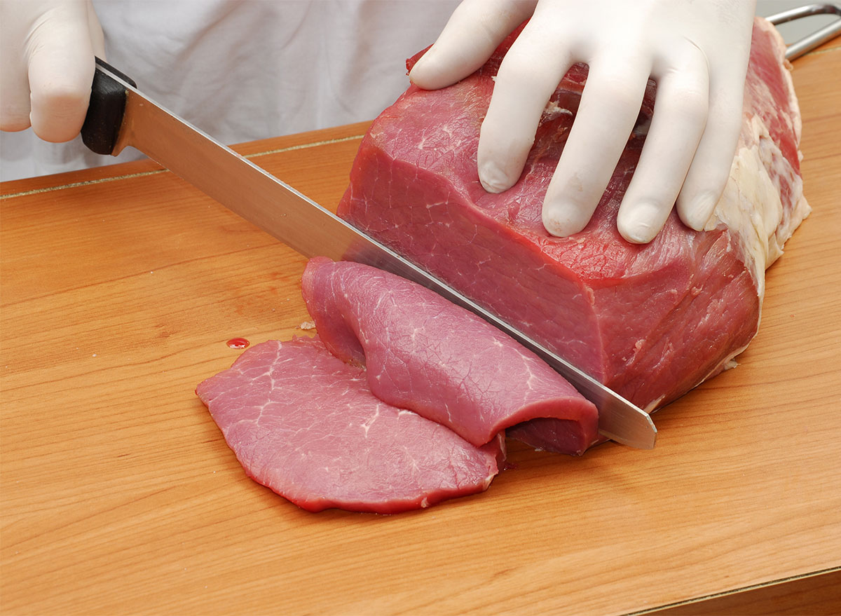 cutting raw meat with gloves