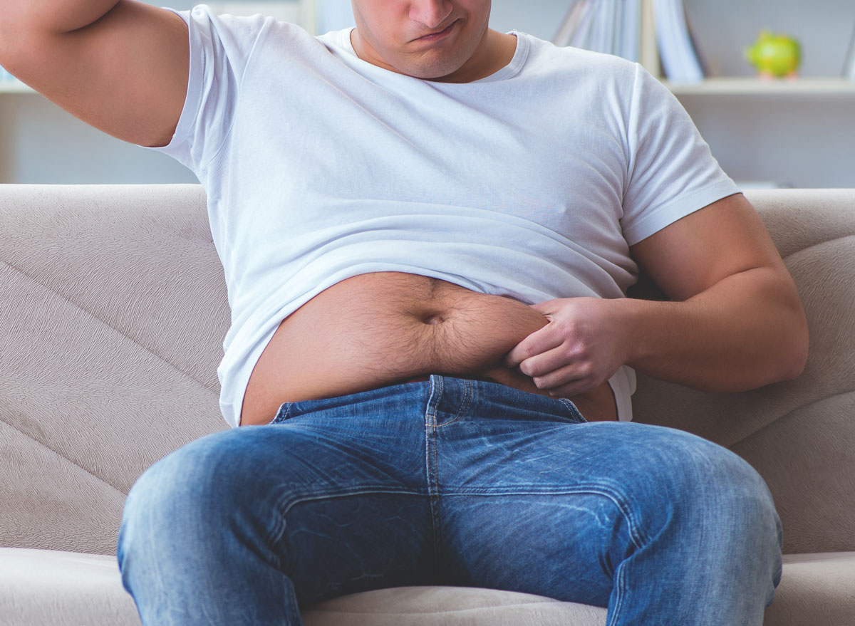Man upset and questioning belly fat as he grabs stomach