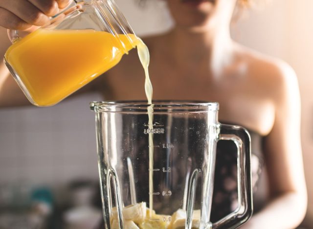 Woman pouring orange juice into a blender