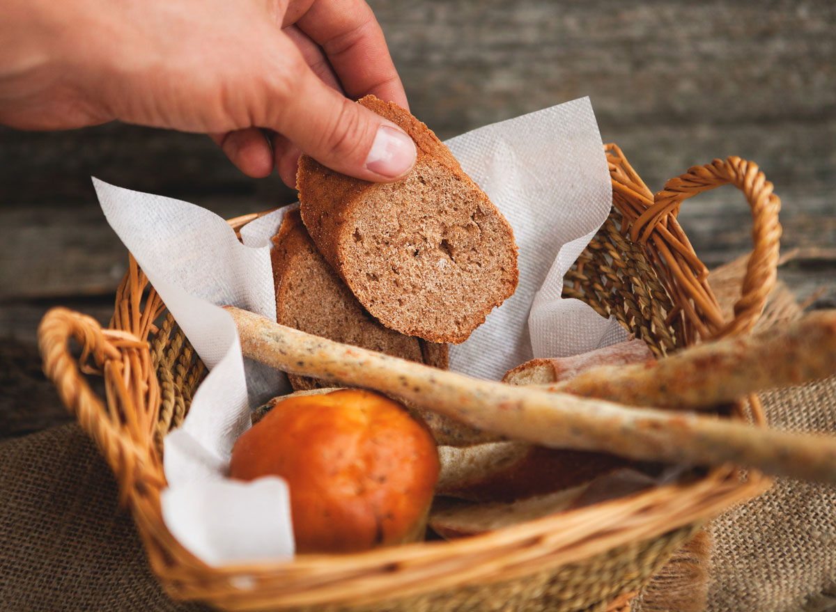Hand reaching for dinner bread roll out of basket