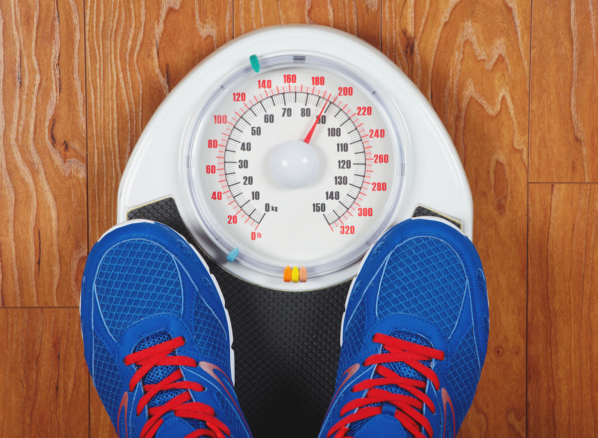 Man weighing himself on scale with shoes on