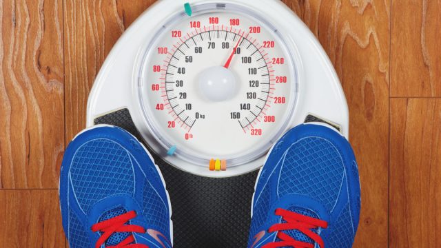Man weighing himself on scale with shoes on