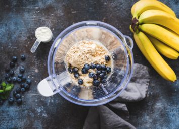 making a smoothie with protein powder blueberries banana in blender