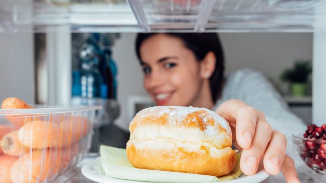 Hungry woman looking for food in fridge