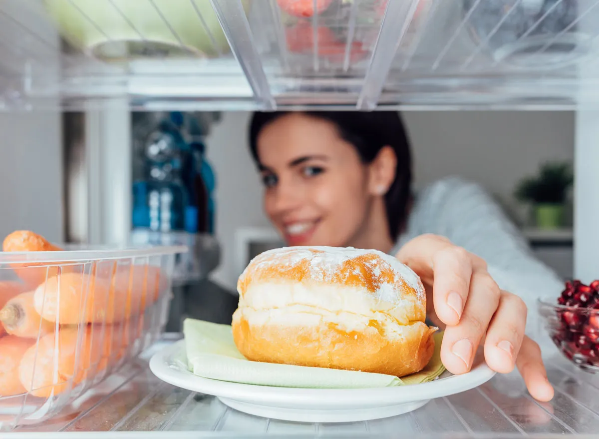 Hungry woman looking for food in fridge