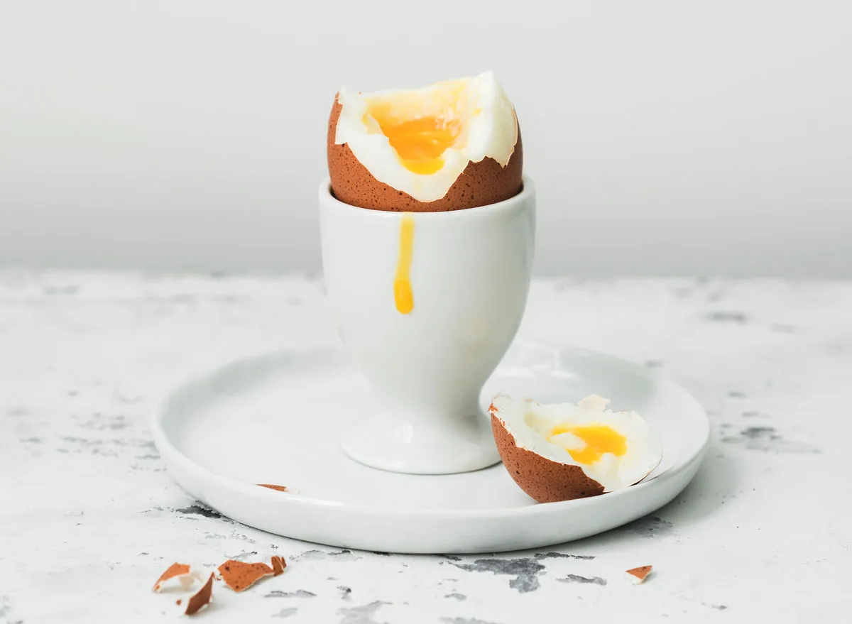 Yolk dripped down soft boiled egg cut open in egg cup