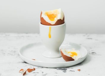 Yolk dripped down soft boiled egg cut open in egg cup