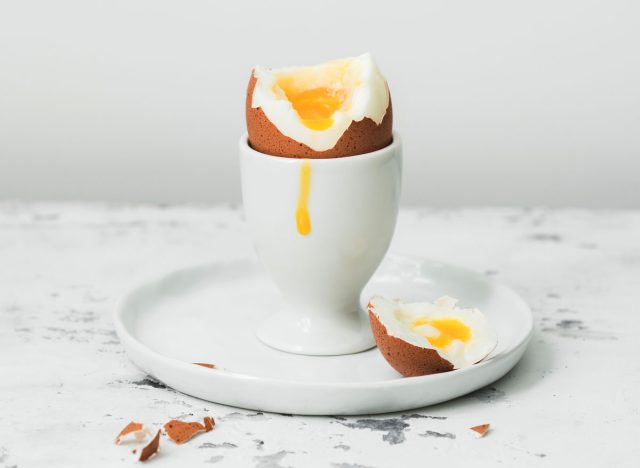 Yolk dripped down soft boiled egg cut open in egg cup