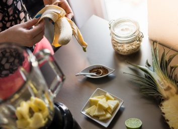 Woman peeling a banana to make a pineapple smoothie