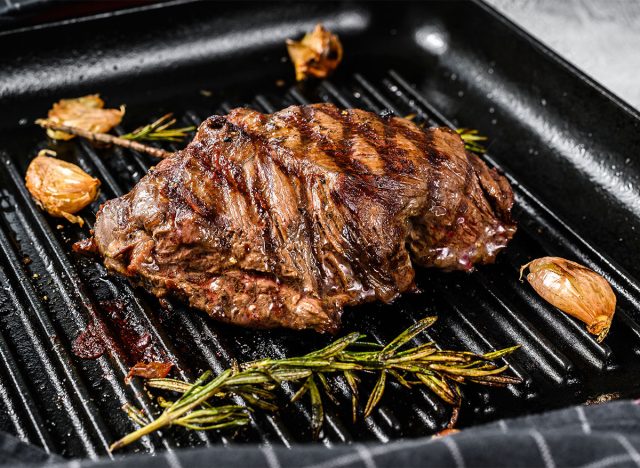 steak on grill with garlic cloves