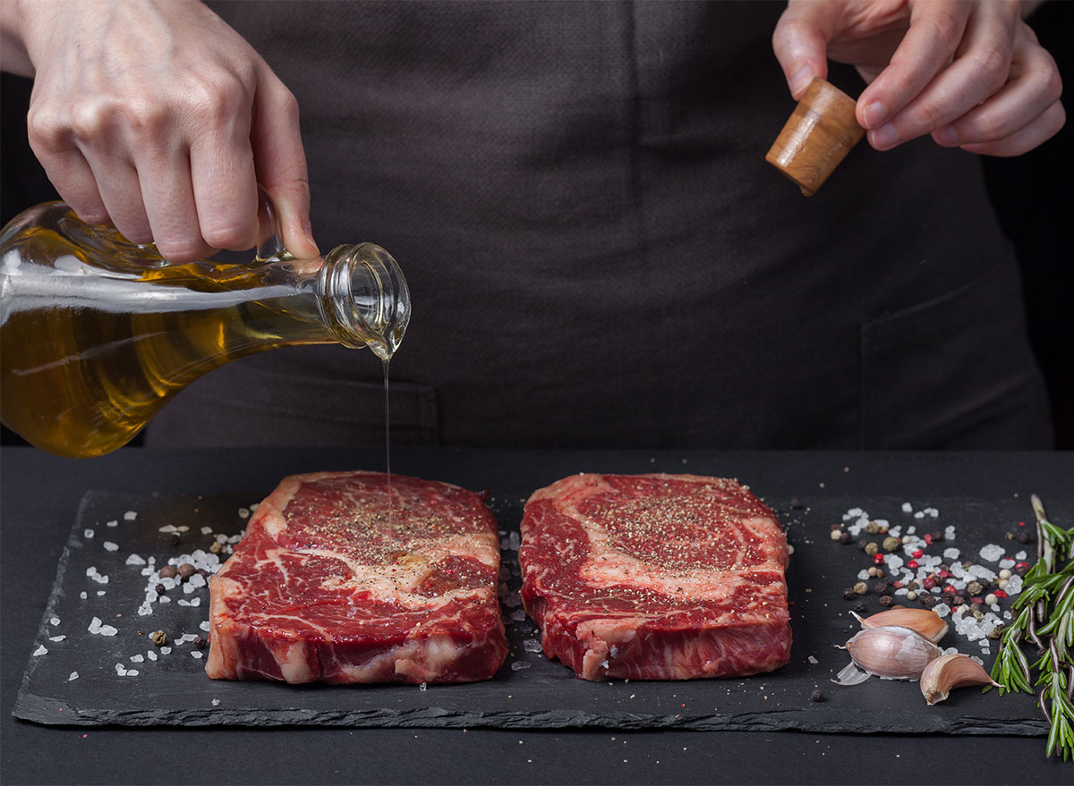pouring olive oil on raw steak