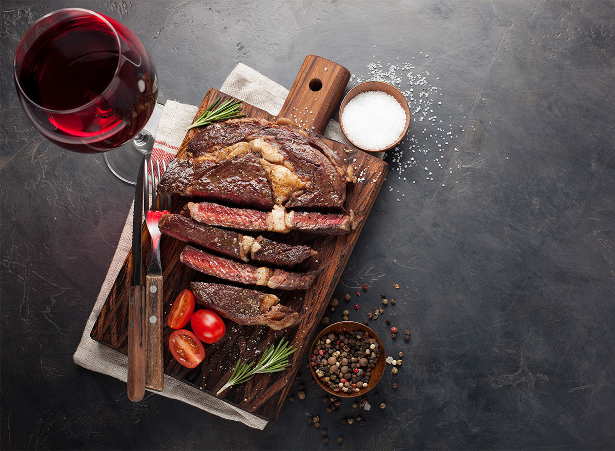 sliced steak with glass of red wine and salt in pinch bowl