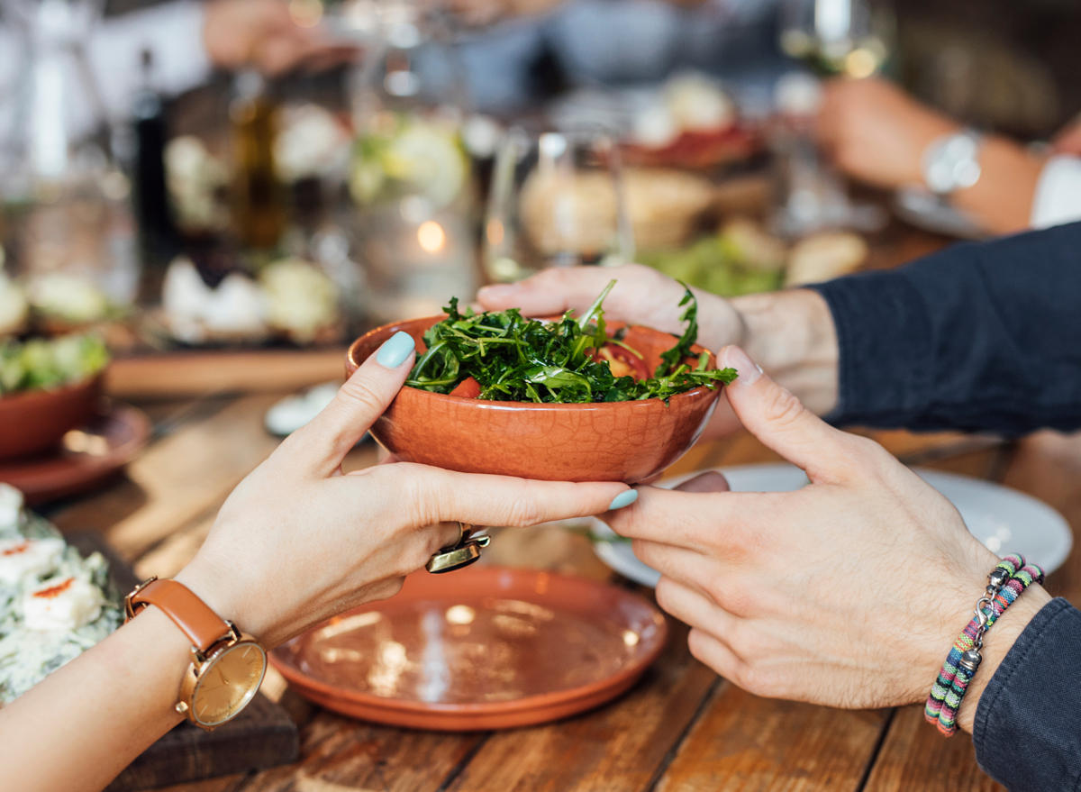 passing side salad across dinner table at vegetarian restaurant