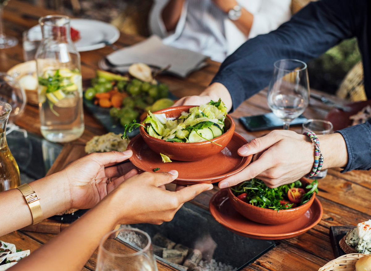 passing side salad across dinner table at vegetarian restaurant