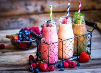 Fruit smoothies in glass jars with mixed berries and paper straws