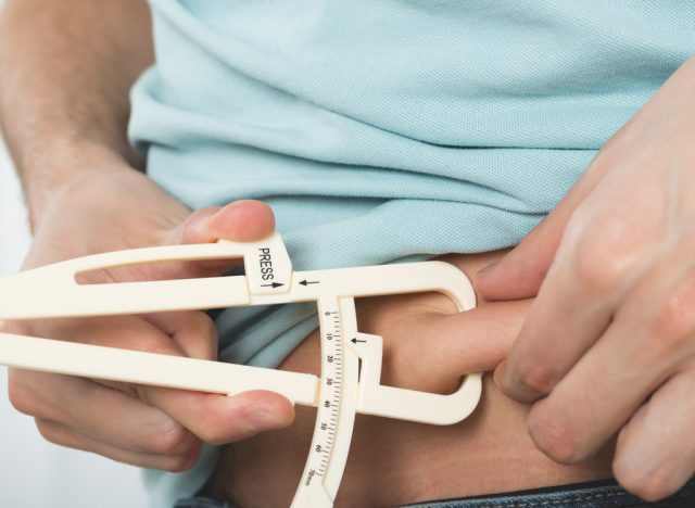 Man measuring belly fat calipers