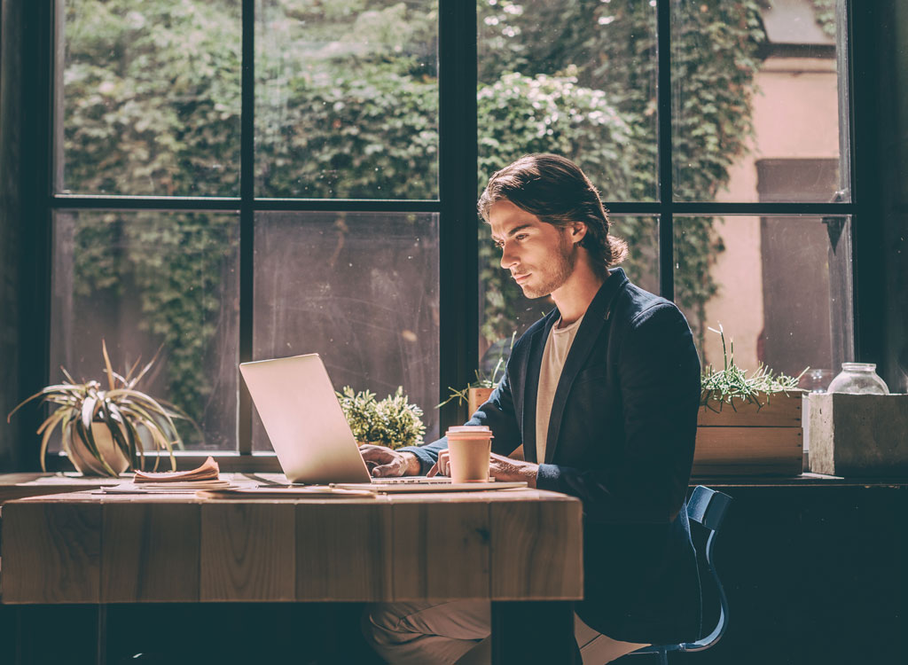 Man working on computer at a window