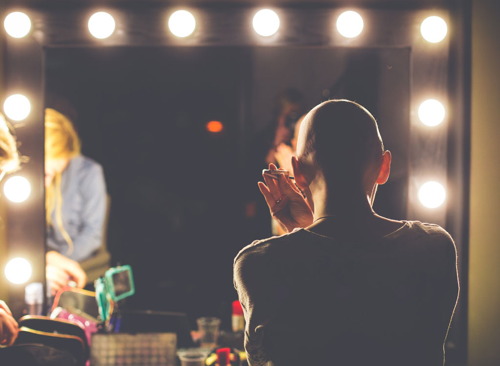 bald woman putting on makeup