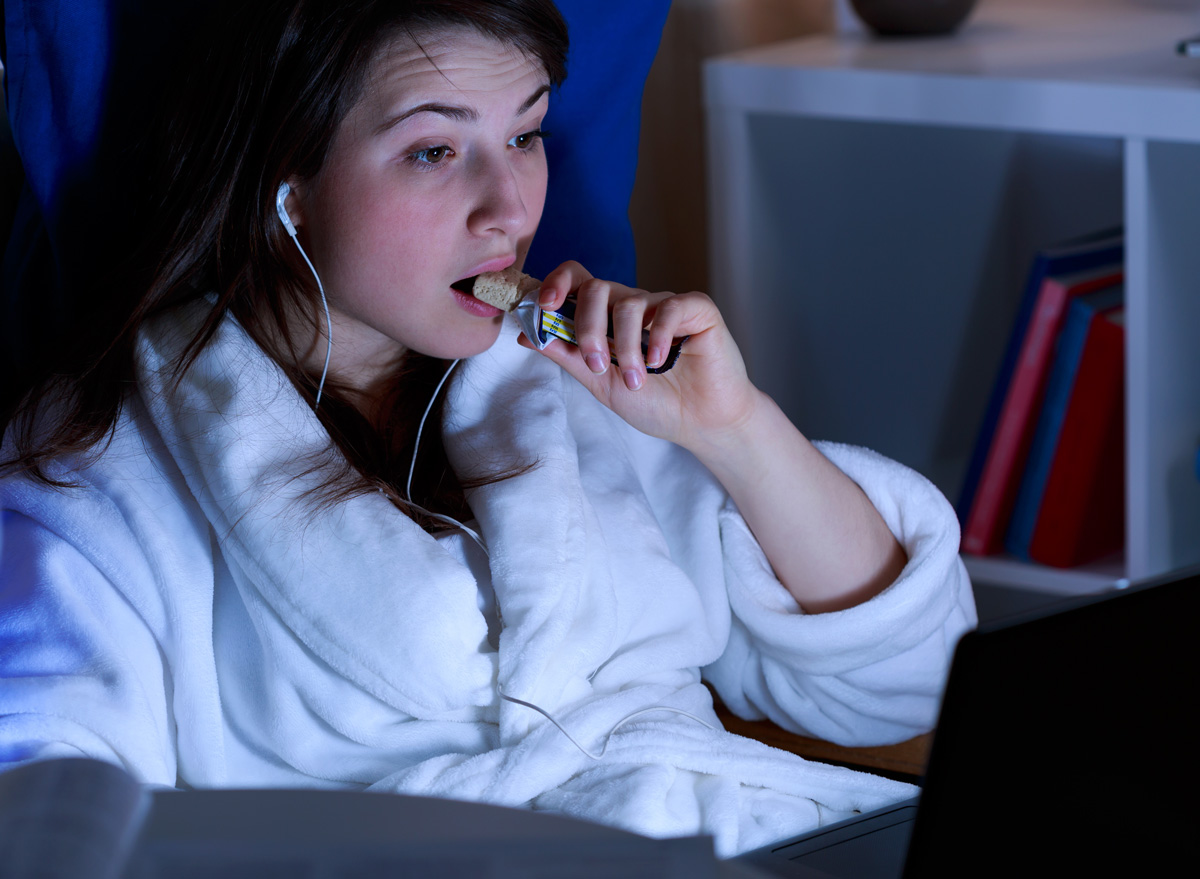 woman eating a healthy protein bar snack before bed sleep