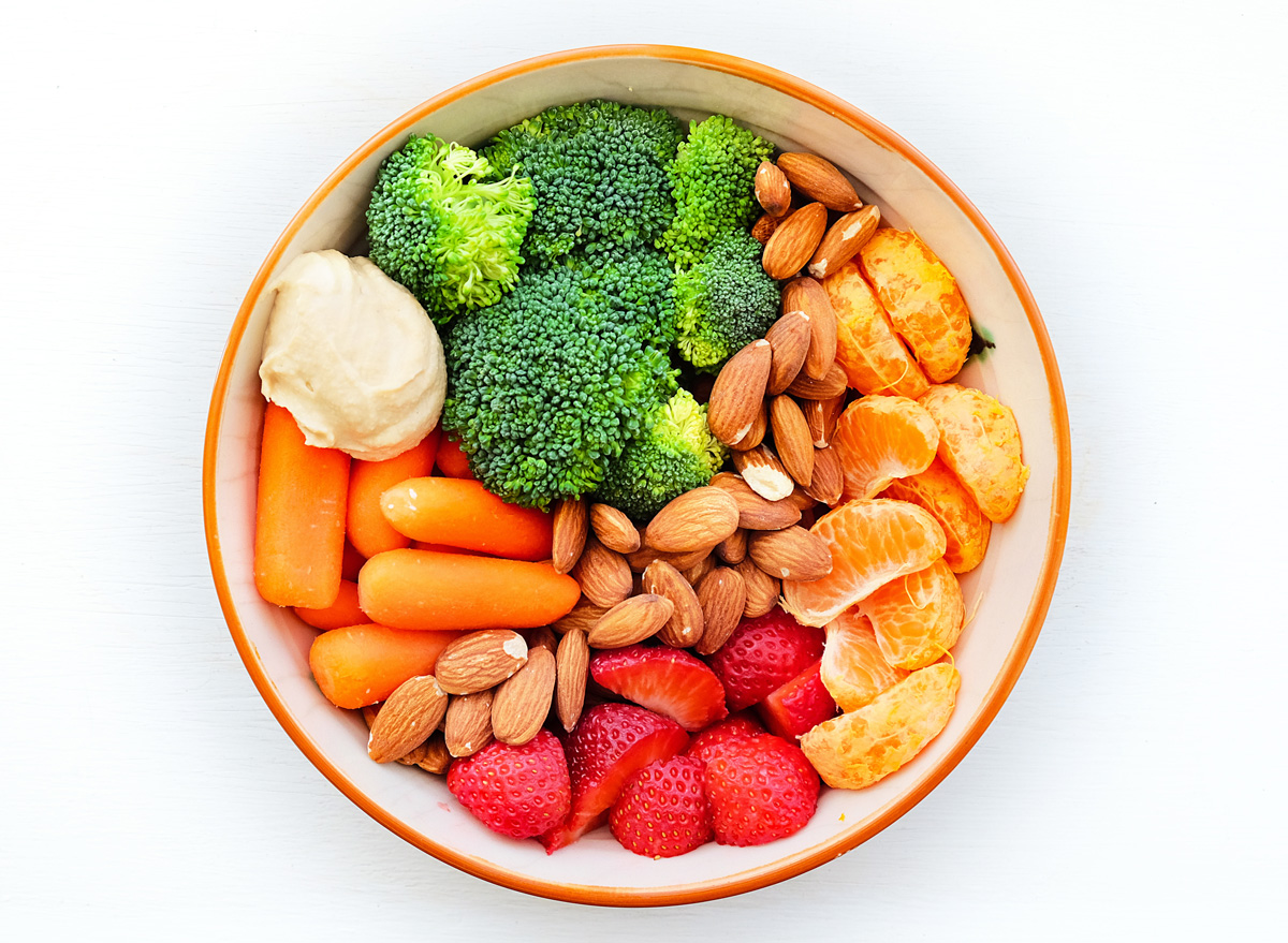 healthy snack bowl with broccoli carrots hummus almonds nuts strawberries fruit
