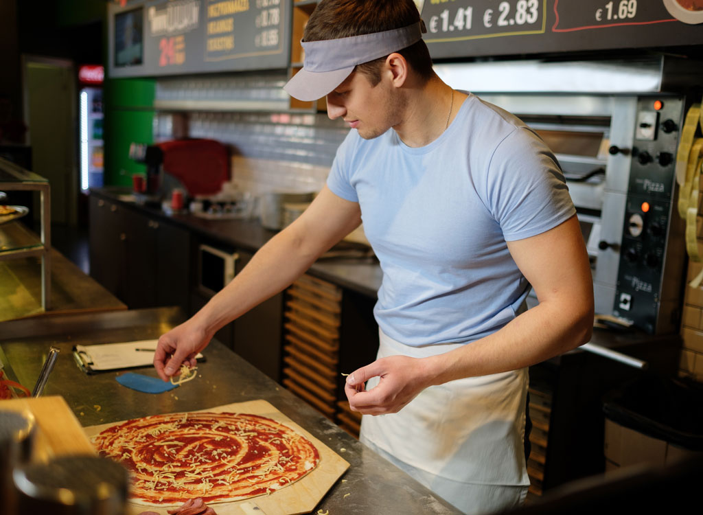 man topping pizza at pizza shop