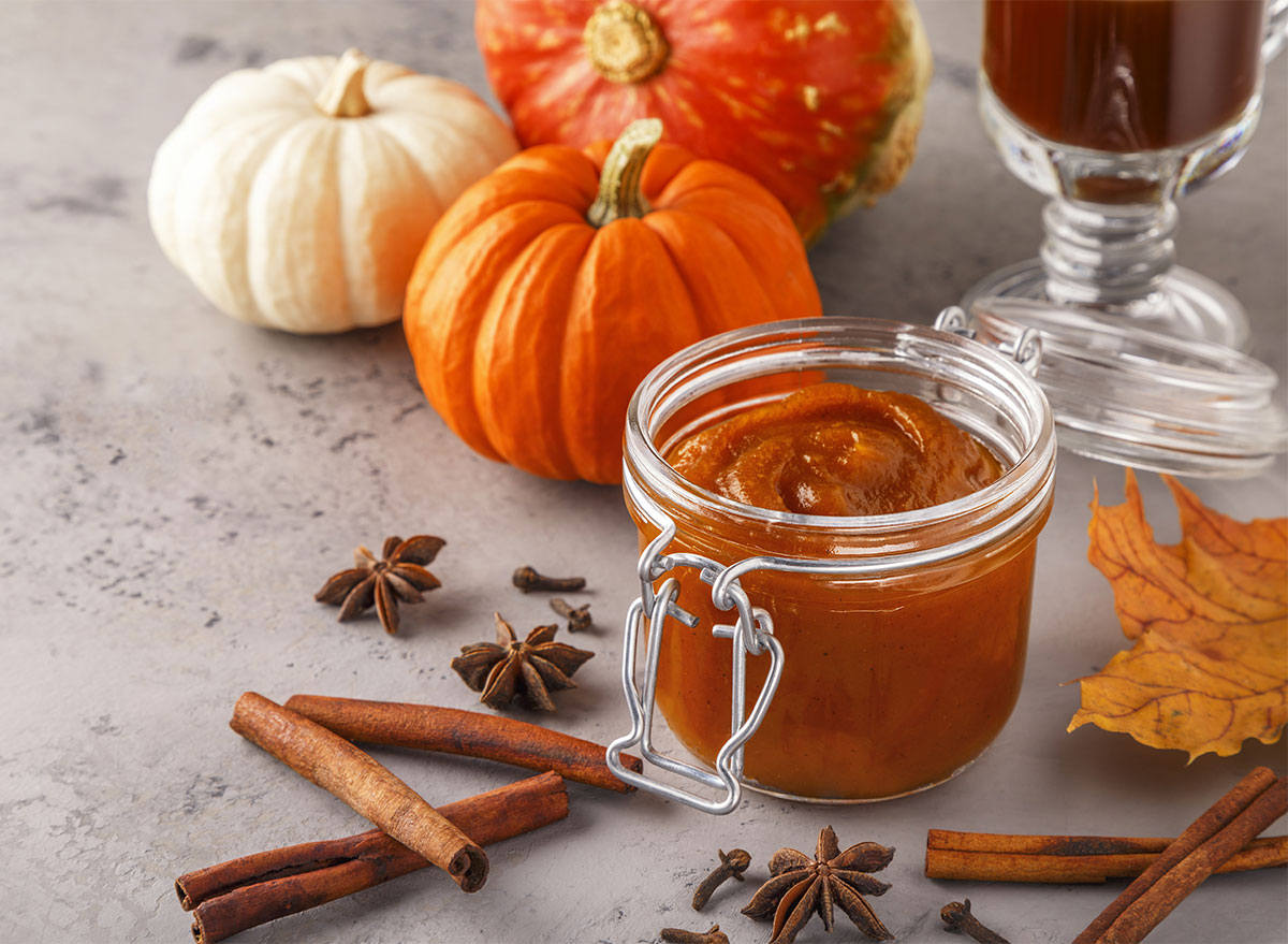 jar of homemade pumpkin butter with mini pumpkins and cinnamon sticks