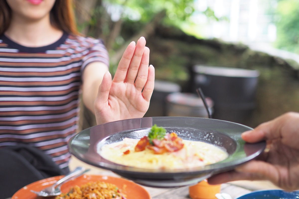 woman pushing away food because she's not hungry