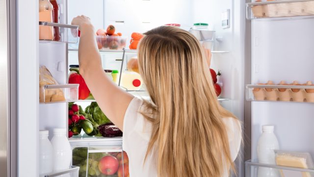 Hungry woman looking for food in fridge