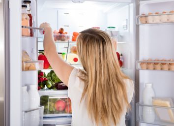 Hungry woman looking for food in fridge