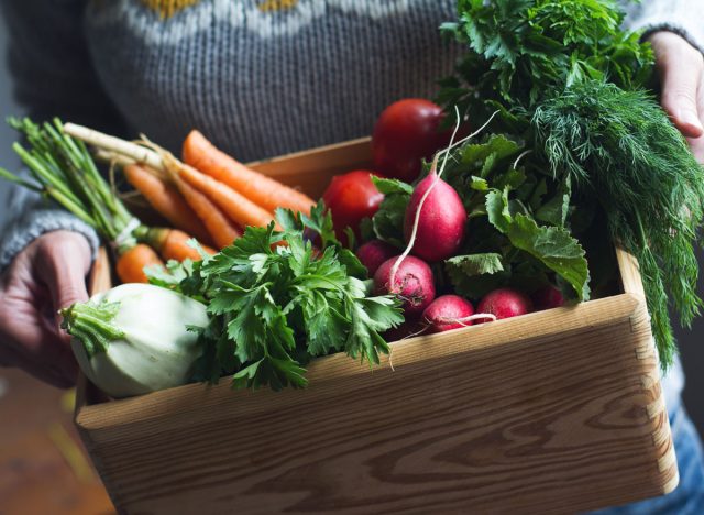 Woman holding csa box of organic fresh vegetables