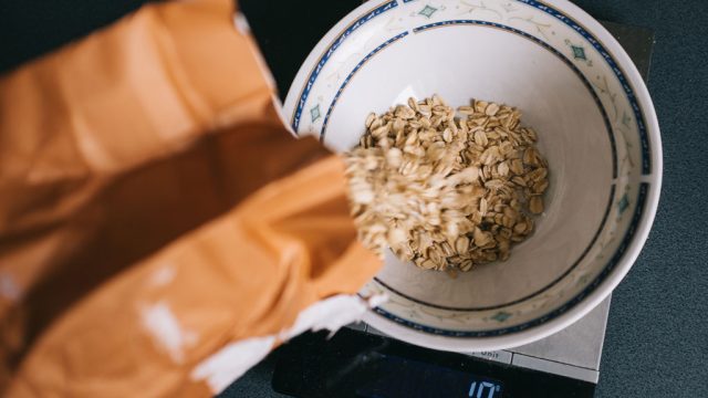 Pouring oats into bowl to measure portion on scale
