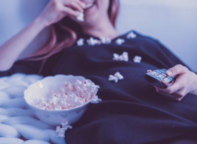 Woman eating popcorn by TV