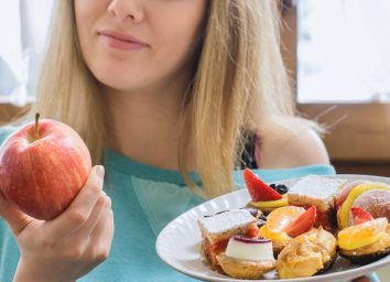 woman choosing healthy apple instead of junk dessert as a food swap to cut calories