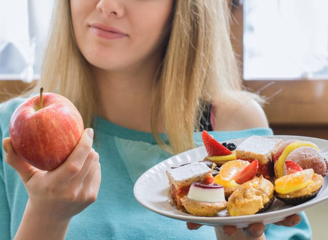 жена, която избира здравословна ябълка вместо безполезен десерт като заместител на храните, които намаляват калориите