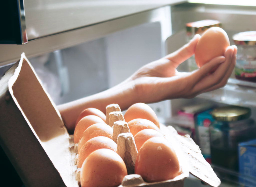 Woman looking at egg in fridge